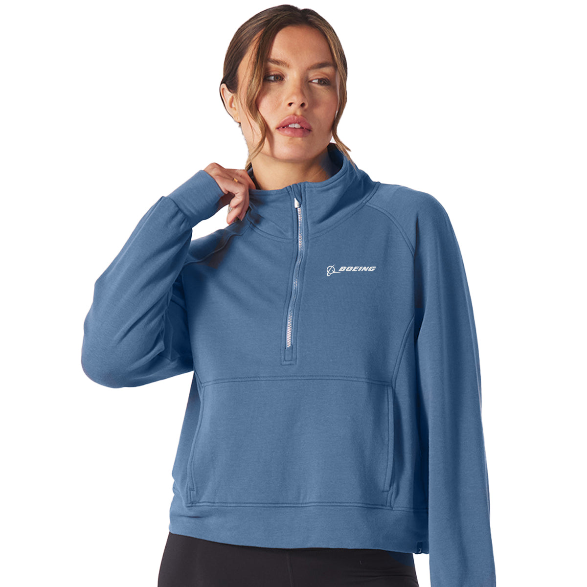 A woman models the Glyder Boeing Womens Daily Quarter-Zip Pullover from The Boeing Store, featuring soft ISOSOF™ plush fabric and a Boeing logo on the chest, standing against a plain background with one hand near her face.