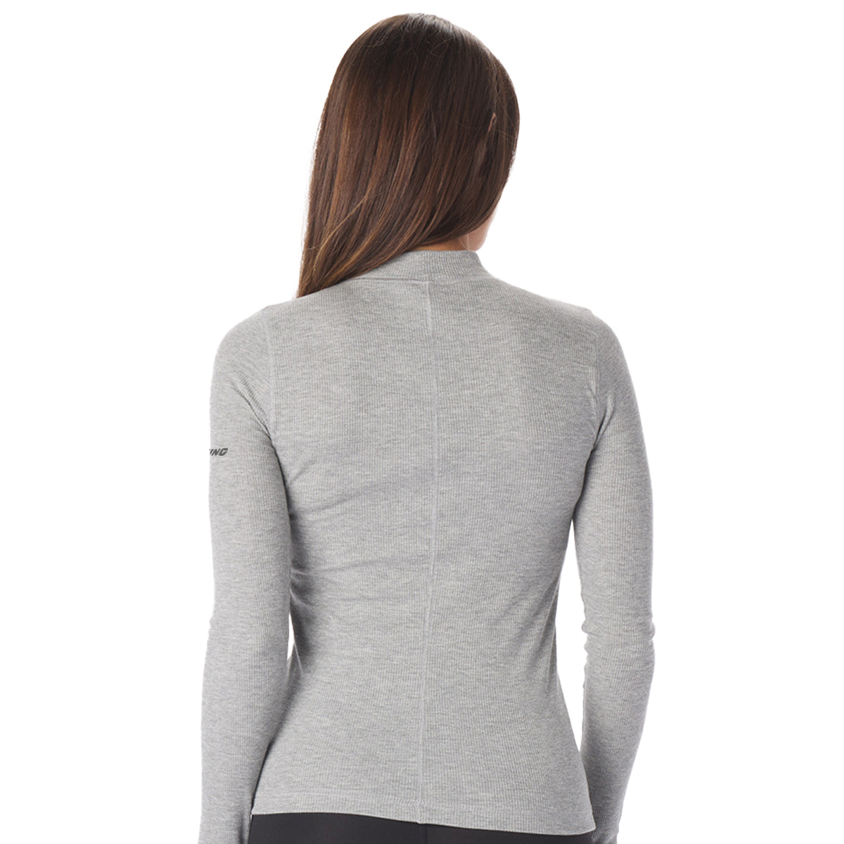A woman with long brown hair stands with her back to the camera, wearing a stylish Glyder Boeing Womens Ruby Mock-Neck Long-Sleeve top from The Boeing Store and black pants against a plain white background.
