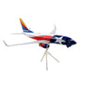 The Daron die-cast metal Southwest Airlines Boeing 737-700 1:200 model features a white backdrop with the airlines iconic red, white, and blue design and star motif. It includes landing gear and is mounted on a tripod stand for authenticity.
