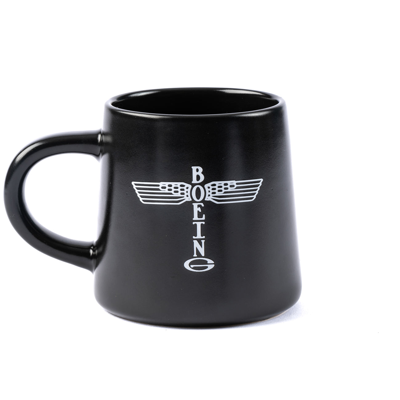 The Boeing Stores black ceramic mug features a white, vertical Boeing Airplane Company Logo with stylized wing graphics. Its microwave and dishwasher safe, boasting a thick handle for convenience.