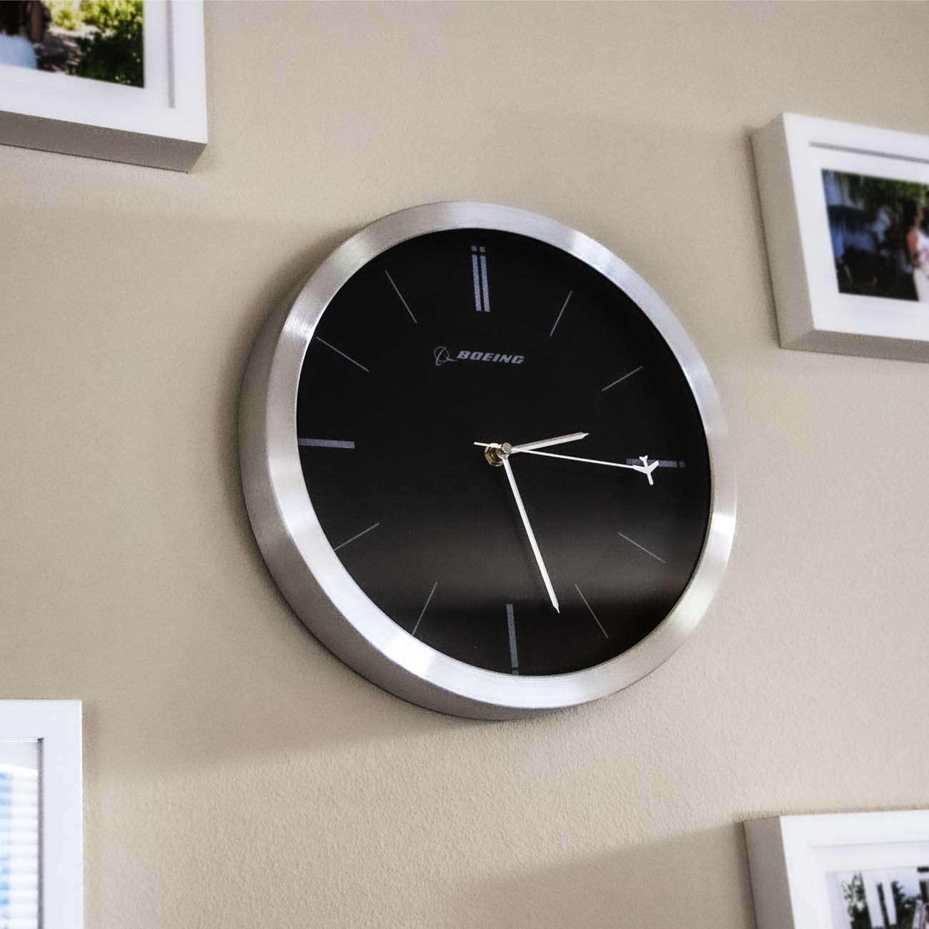 The Boeing Rotating Plane Clock from The Boeing Store features a black face, silver frame, minimal markings, and an airplane-shaped second hand—making it a unique wall clock that's perfect for aviation enthusiasts.