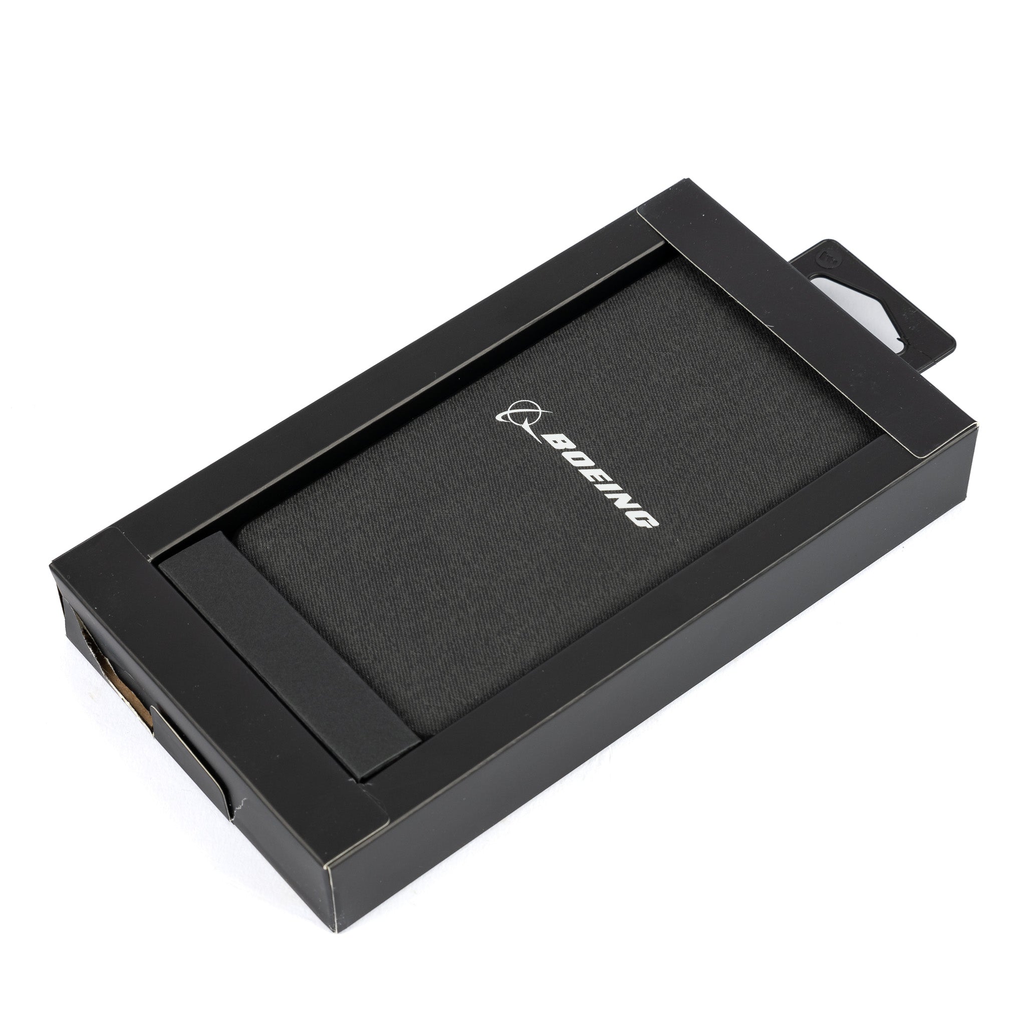 A black, rectangular box with a transparent window showcases the Mophie Boeing Powerstation XXL Power Bank inside. The power bank, featuring the white Boeing logo on its textured surface, offers USB ports for easy connectivity. The packaging maintains a sleek, minimalist design.