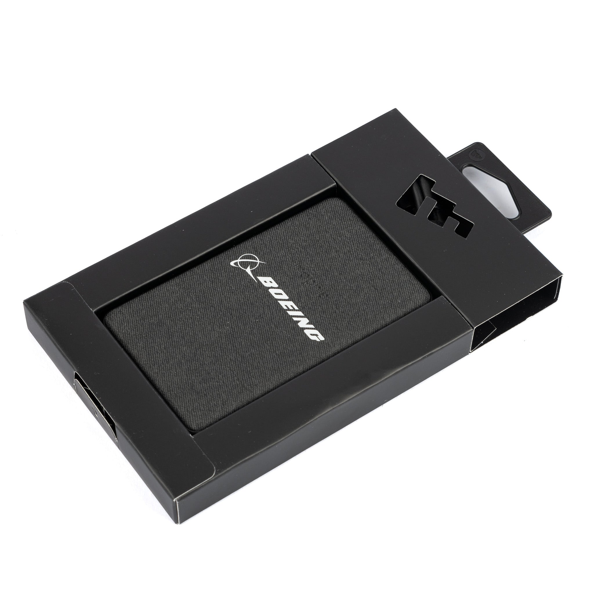 A black box with a transparent window displays the Mophie Boeing Snap+ Juice Pack Mini Power Bank inside. Adorned with a white Boeing logo, it sits securely in packaging featuring a cutout hanger at the top. Available at The Boeing Store, its MagSafe compatible.