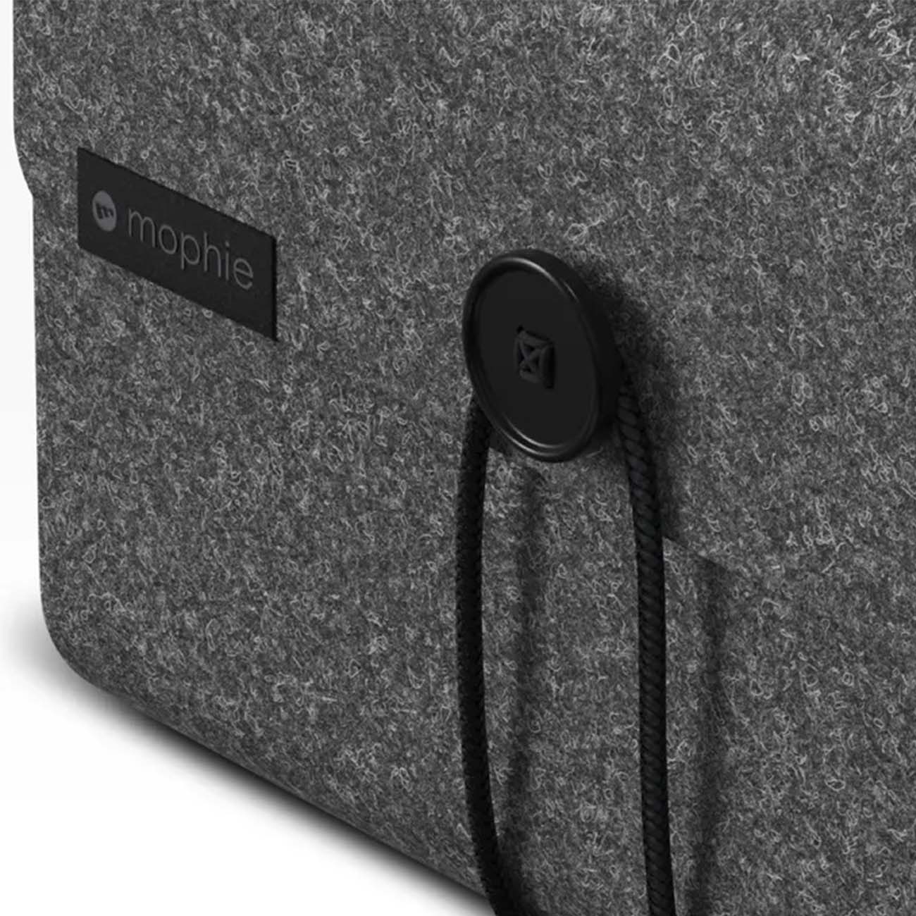 Close-up of a gray felt bag featuring a black circular button and two black cords, ideal for organizing your travel charger. The Mophie Boeing 3-in-1 Travel Charger brand is elegantly displayed on a black label attached to the bag by The Boeing Store.