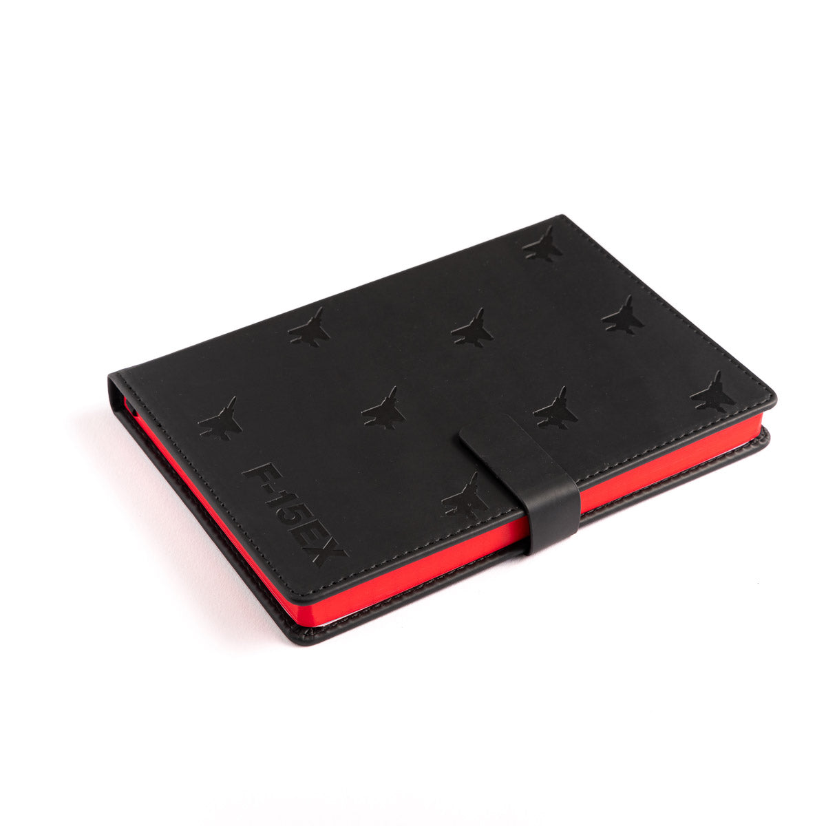 The Boeing F-15EX Eagle Notebook from The Boeing Store is a black leather notebook with butterfly cutouts and red edges. It features a strap closure and Moleskine embossed on the bottom left, elegantly resting against a white background like a sleek Boeing aircraft.