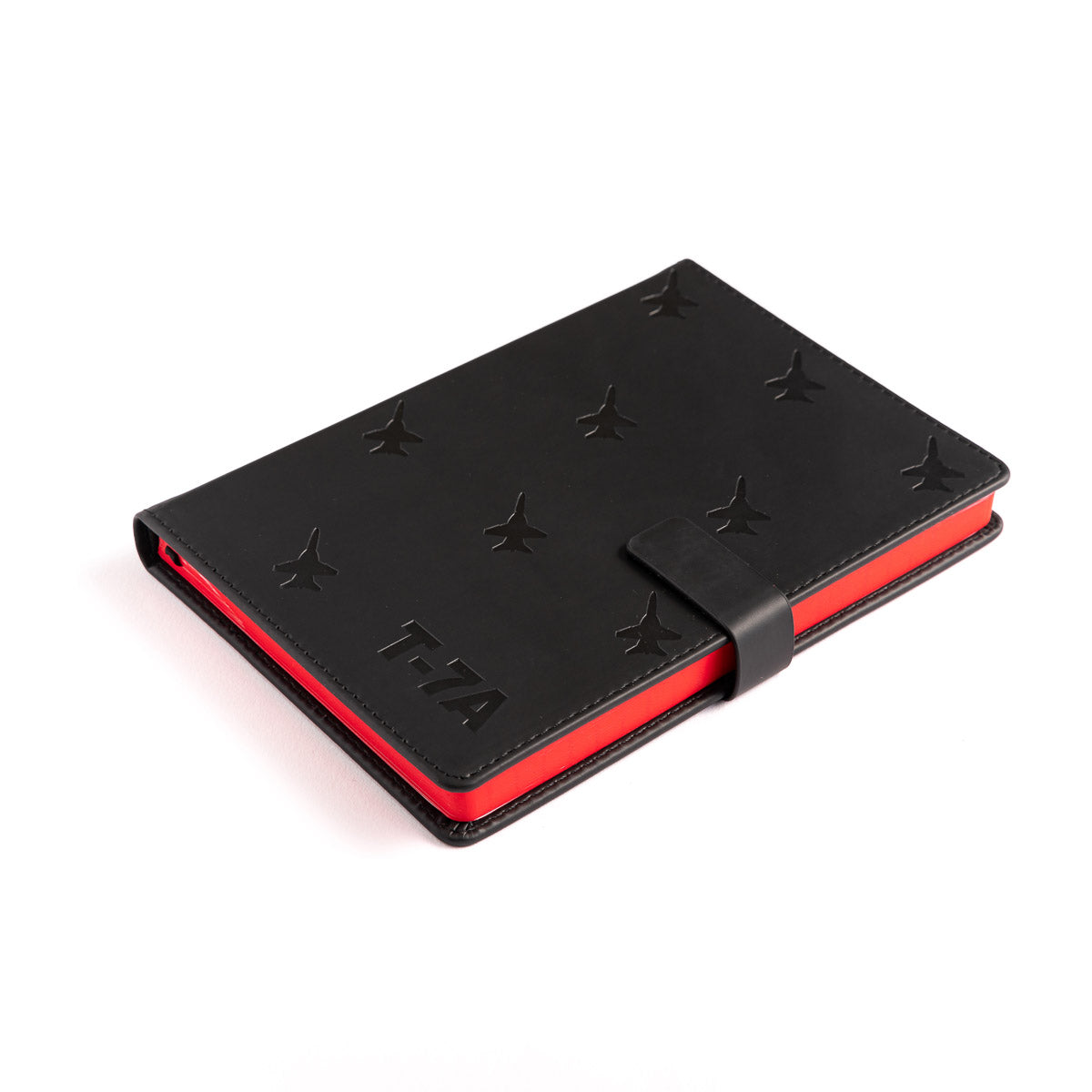 The Boeing Stores Boeing T-7A Red Hawk Notebook is a black notebook with star patterns, T7A embossed on the cover, and inspired by Boeings design. It features a red edge and secure black strap closure.