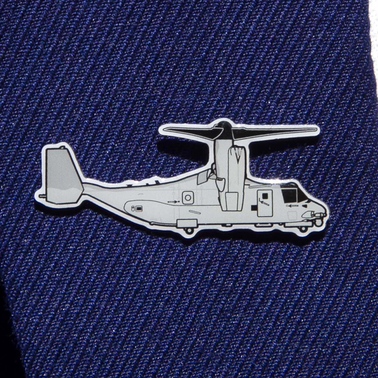 The Boeing Stores silver tone Boeing Illustrated V-22 Lapel Pin, resembling a military aircraft and enhanced with an epoxy finish, is attached to a dark blue suit fabric.
