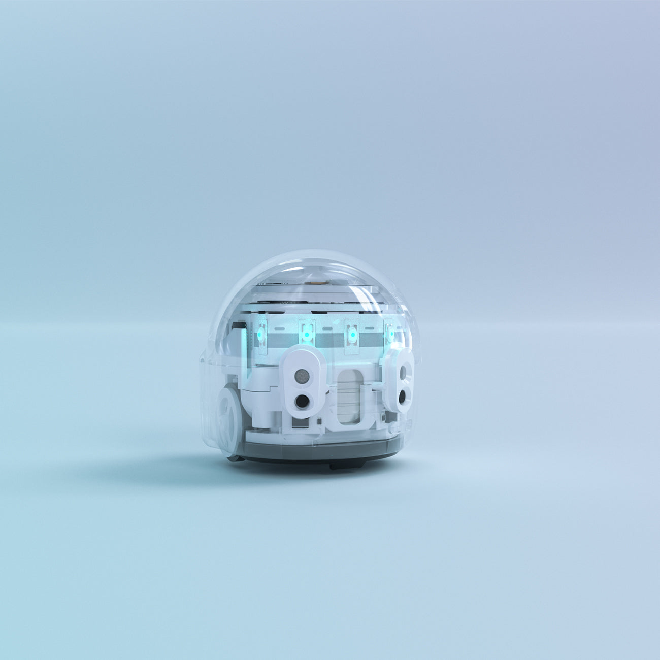 A small, white, dome-shaped Ozobot Evo coding robot from The Boeing Store reveals its internal components through a clear casing against a light blue background. Its design hints at the possibilities unlocked with OzoBlockly programming or the intuitive Evo app.