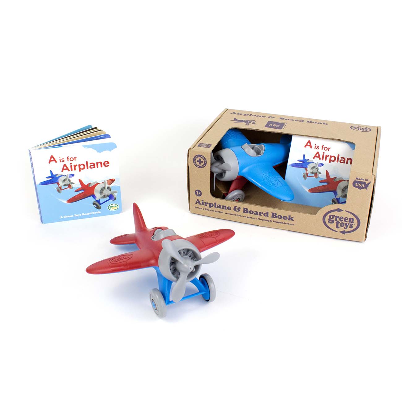 A red toy airplane and a blue Green Toys™ Airplane from The Boeing Store are showcased alongside the board book A is for Airplane. The airplanes recycled-material box has a transparent front, and the book stands upright beside it.