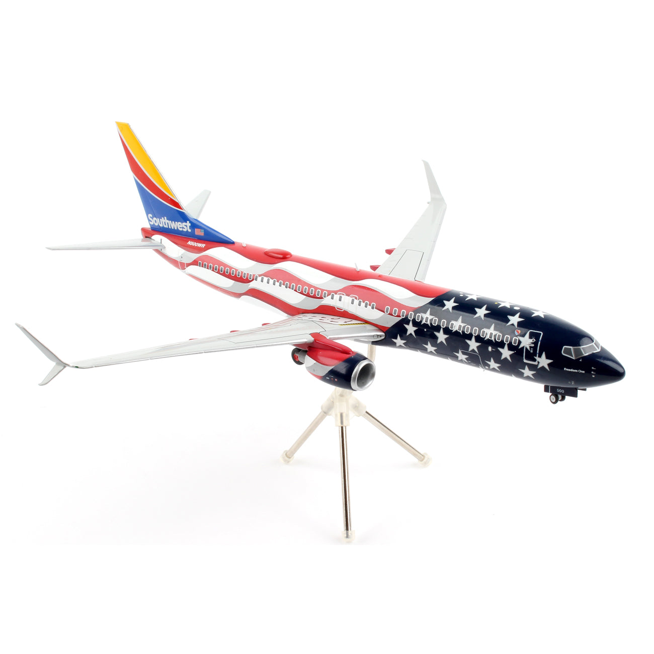The Daron Southwest Airlines Boeing 737-800 Freedom model, at a 1:200 scale, features a patriotic American flag design on its fuselage, includes landing gear, and is mounted on a sleek, three-legged stand.