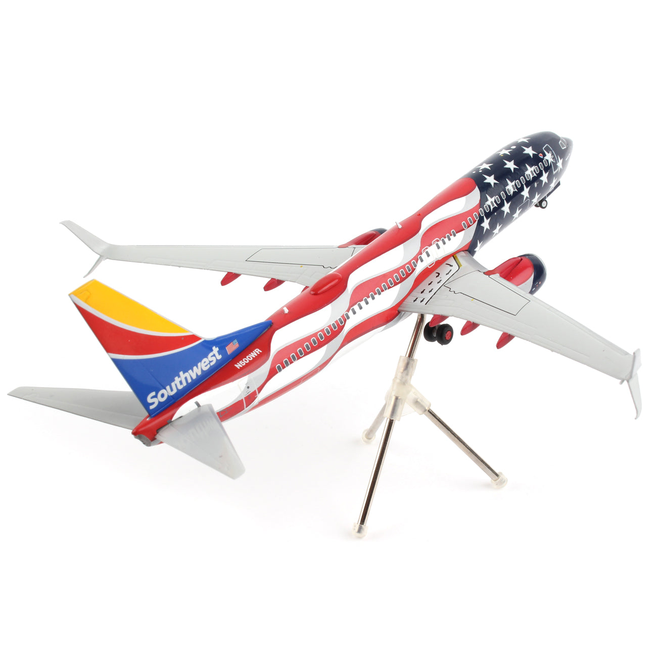 The Daron Southwest Airlines Boeing 737-800 Freedom model features a red, white, and blue American flag motif with a mounted stand. This 1:200 scale die-cast plane is displayed from the rear with its landing gear retracted, angled slightly upward.