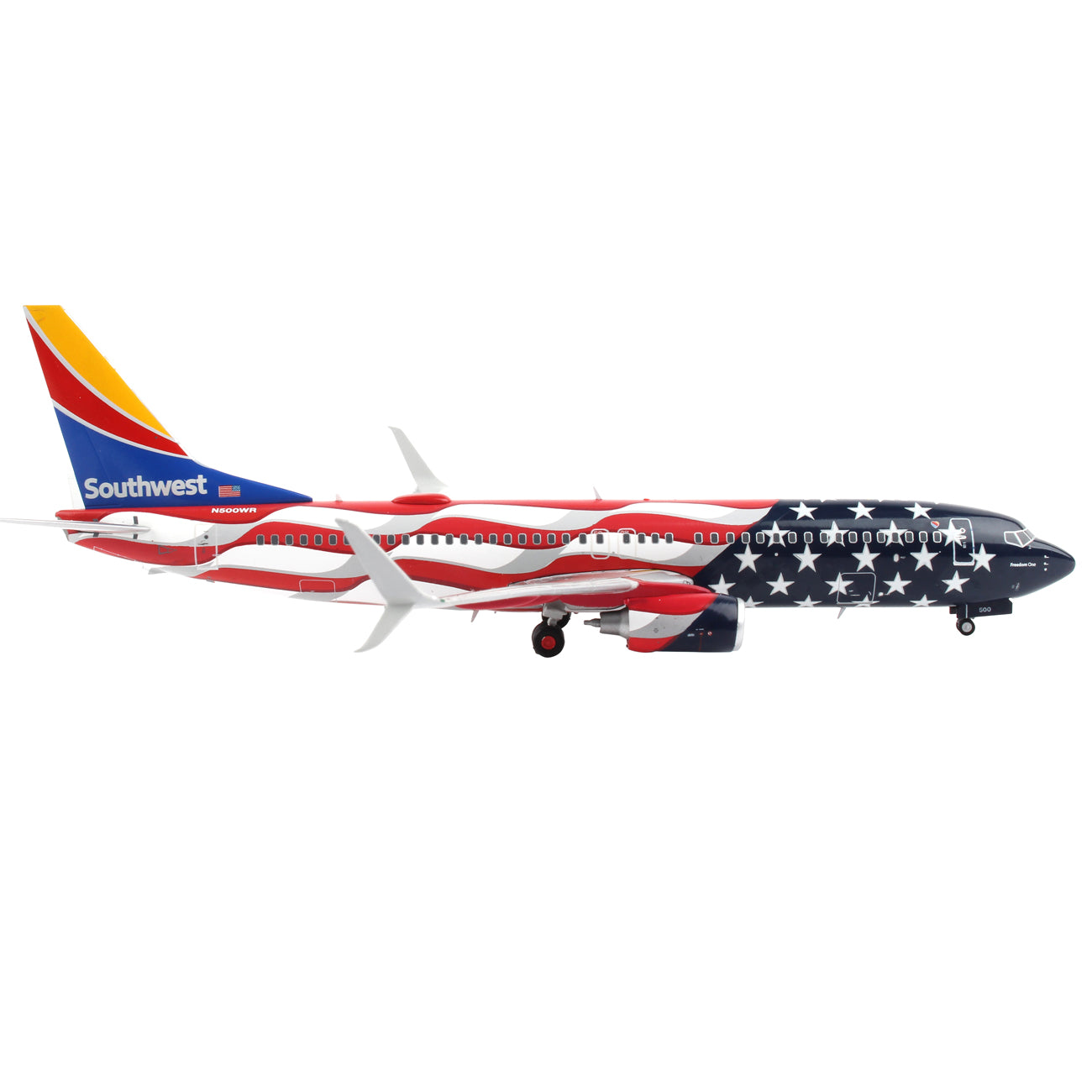 Side view of the Daron Southwest Airlines Boeing 737-800 Freedom die-cast model, 1/200 scale, featuring the American flag design with red and white stripes, stars on a blue field, and a tail in yellow, red, and blue. Meticulously crafted landing gear details against a white background.