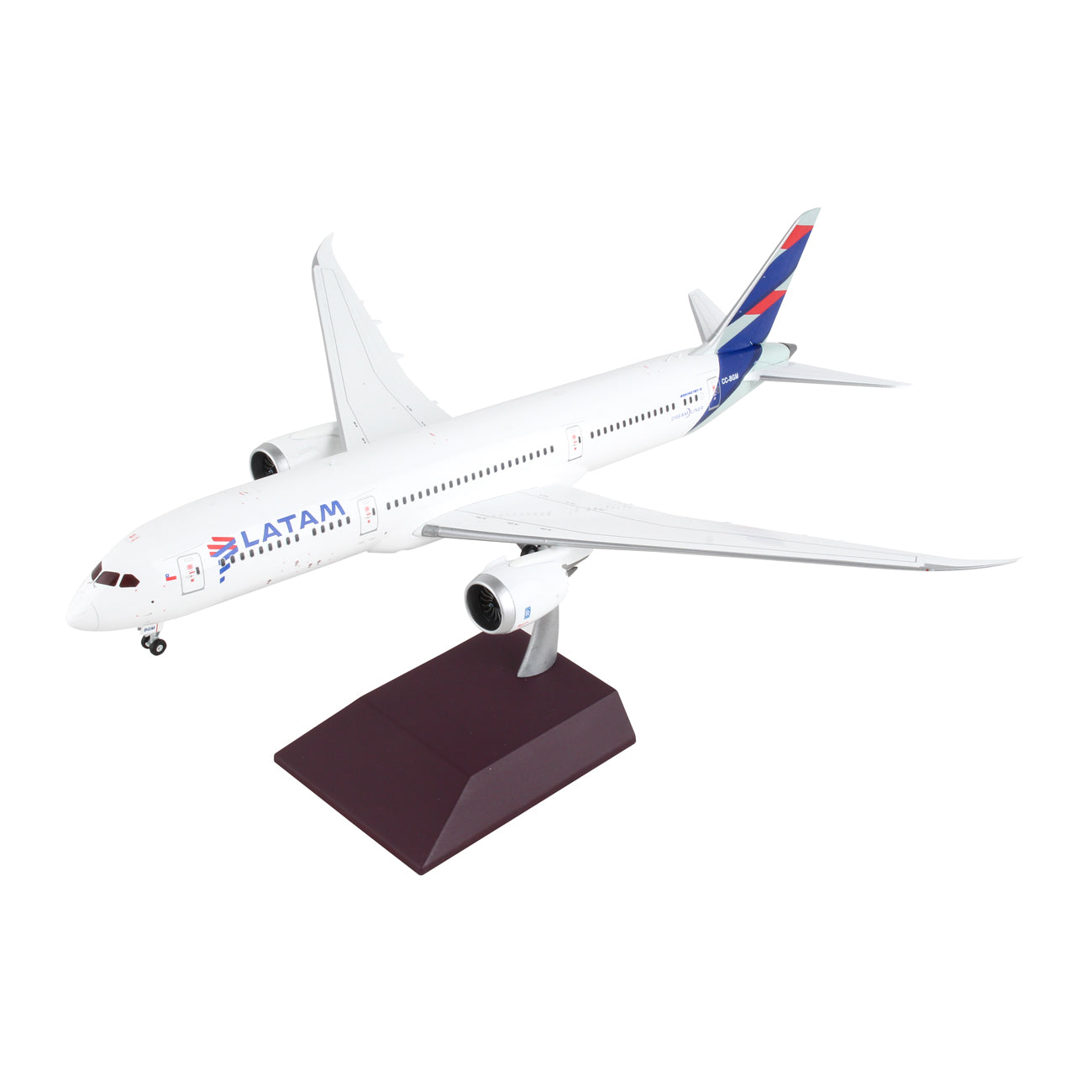 The Daron LATAM Airlines Boeing 787-9 1:200 die-cast model features detailed landing gear, a white body with blue and red tail, and comes mounted on a brown display stand against a white background.
