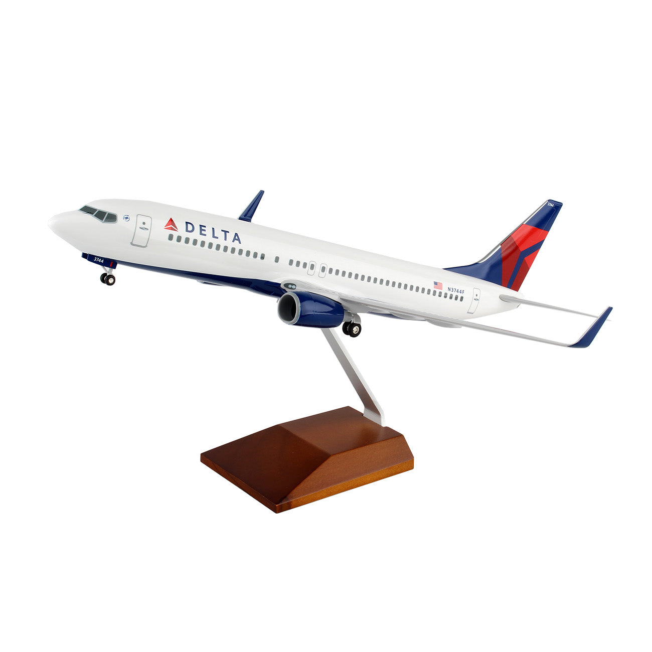 The Daron Delta Air Lines Boeing 737-800 1:100 Model features white paint with blue and red accents, mounted on a wooden stand in a flight pose—ideal for aviation collectors.