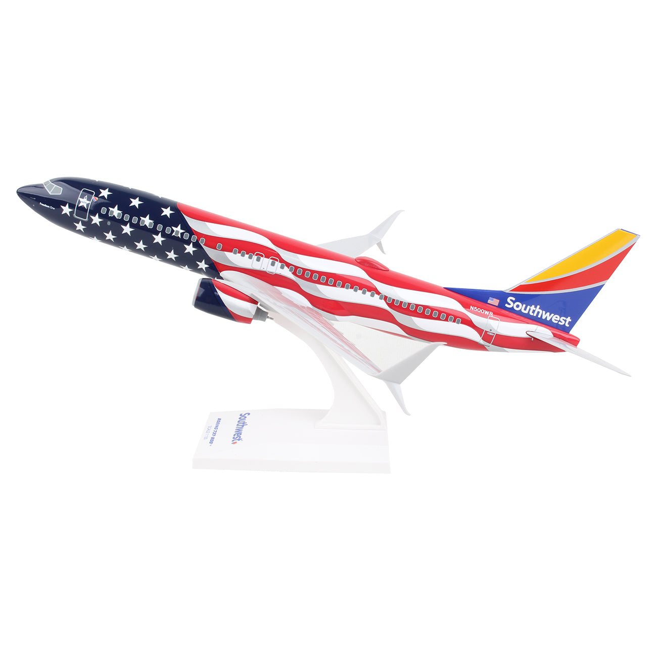 The Daron Southwest Airlines Boeing 737-800 Freedom 1:130 Model features a unique American flag design, with a colorful red, yellow, and blue tail. It sits on a white stand labeled Southwest and boasts detailed graphics ideal for collectors.
