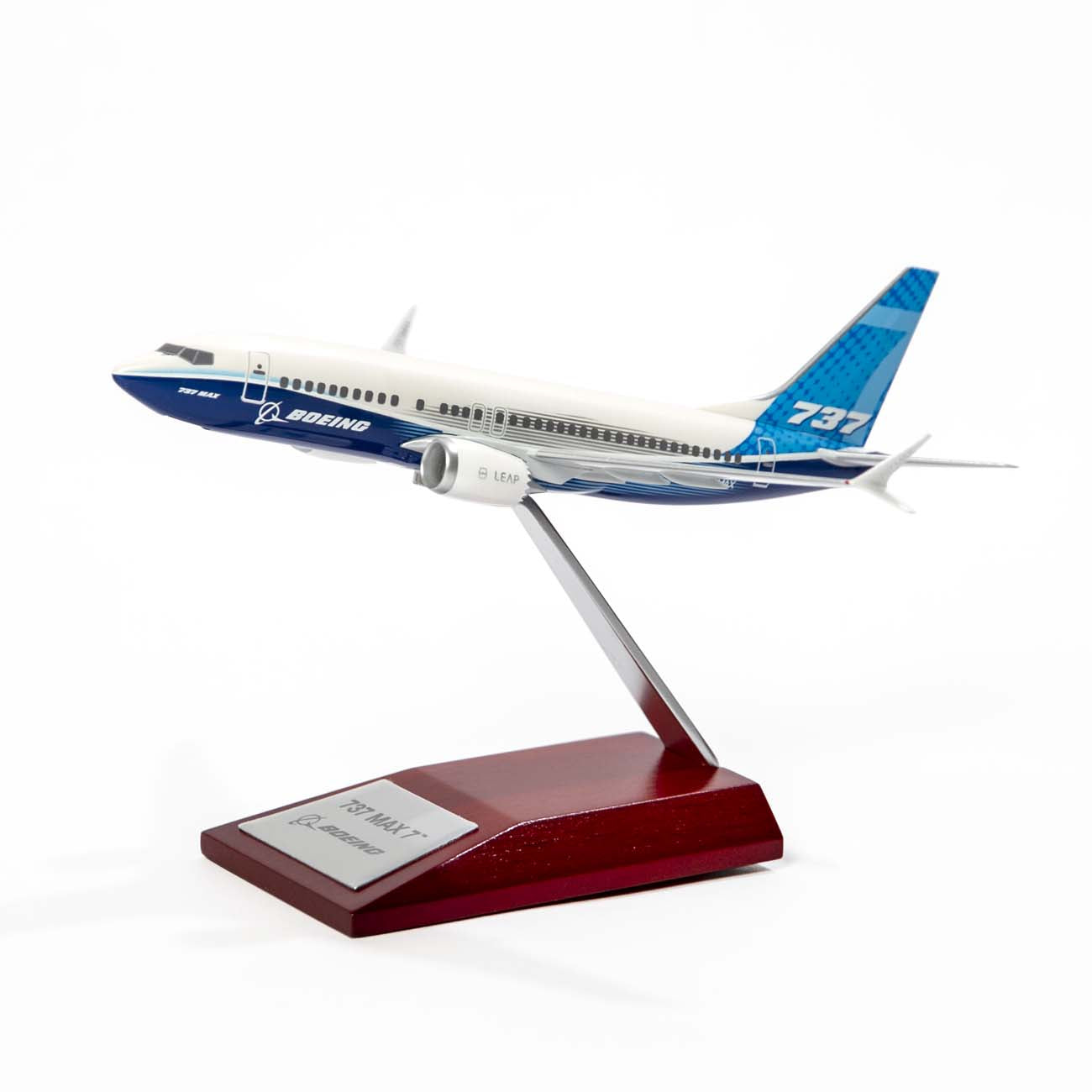 The Boeing Stores exquisite Boeing Unified 737 MAX 7 1:200 Model rests on a wooden stand against a plain white backdrop. Painted in classic blue and white, it proudly showcases its renowned fuel efficiency as it bears 737 MAX 7 on its tail.
