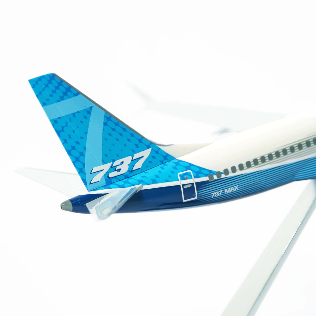 A close-up of The Boeing Stores Boeing Unified 737 MAX 7 1:200 Model showcases the blue and white tail with 737 pattern. The fuselage bears 737 MAX 7, emphasizing its famed fuel efficiency against a minimalist white backdrop.