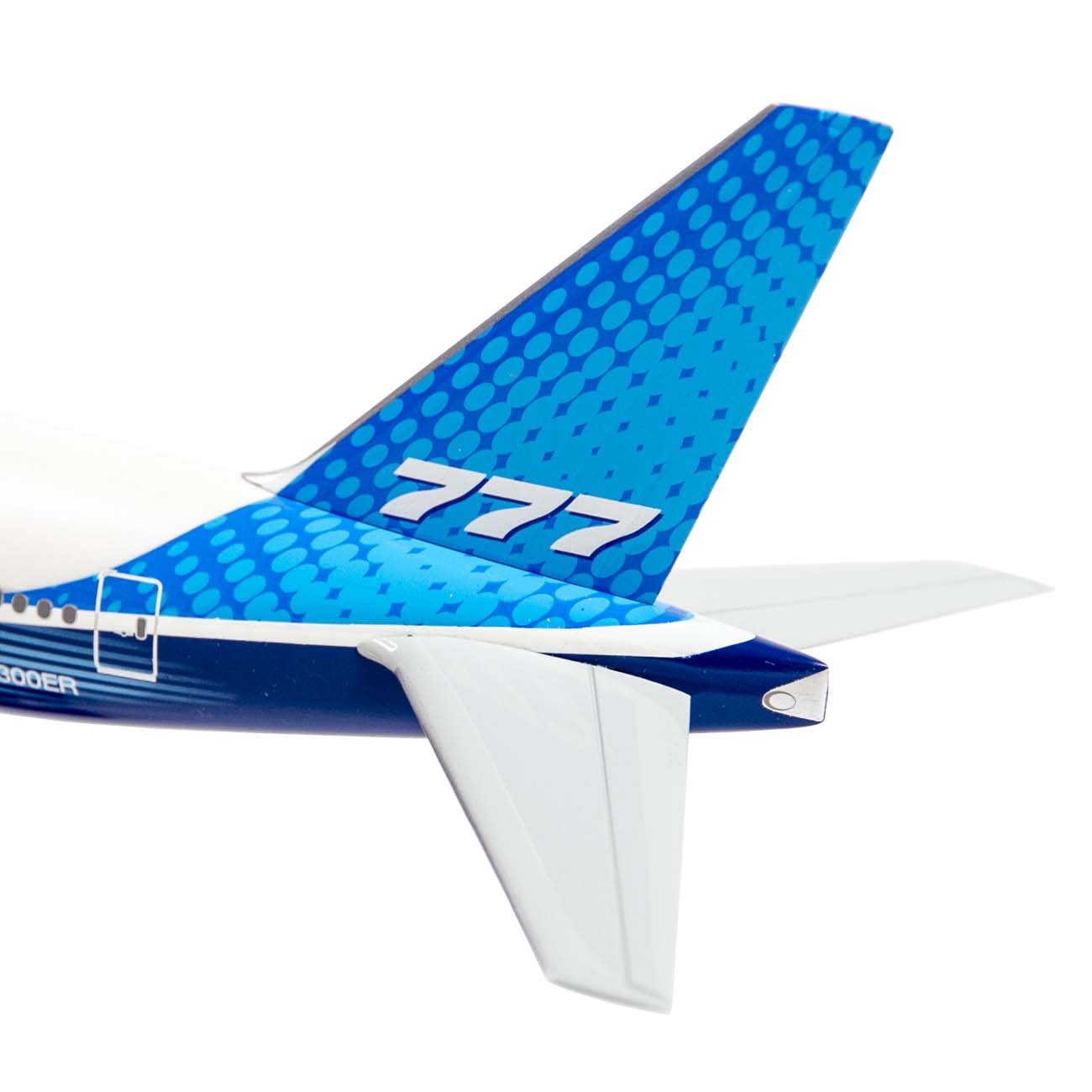 Close-up of the Boeing Store’s Boeing Unified 777-300ER 1:200 Snap Model showing its blue dotted tail fin with "777" in white, visible horizontal stabilizers, and part of the model’s fuselage.