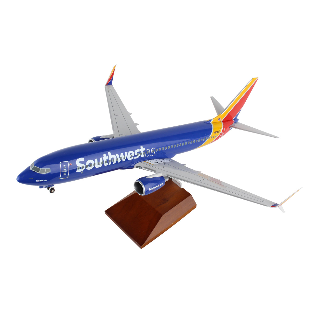 The Daron Southwest Airlines Boeing 737-800 1:100 Model features a blue fuselage with bold white Southwest text and a vibrant red, yellow, and blue tail. It includes spinning engines and is elegantly displayed on a wooden stand.