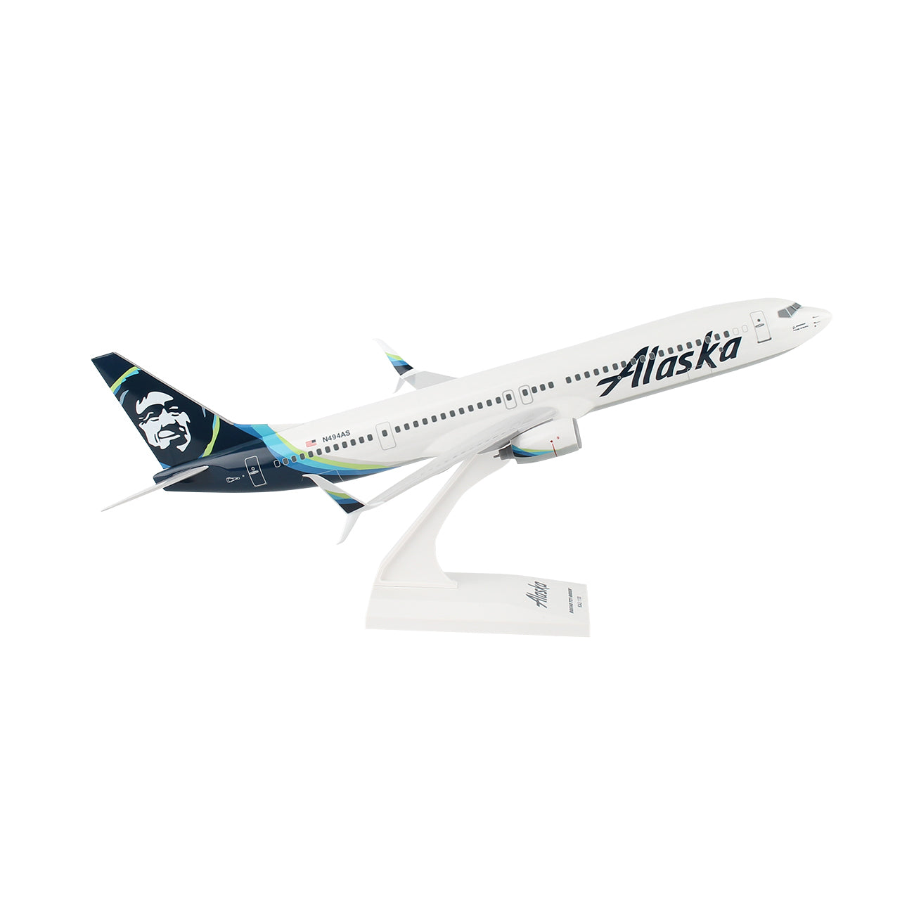 The Daron Alaska Airlines Boeing 737-900ER 1:130 Model features detailed white, blue, and green graphics, Alaska branding on the fuselage, a stylized face on the tail, and comes mounted on a white stand.