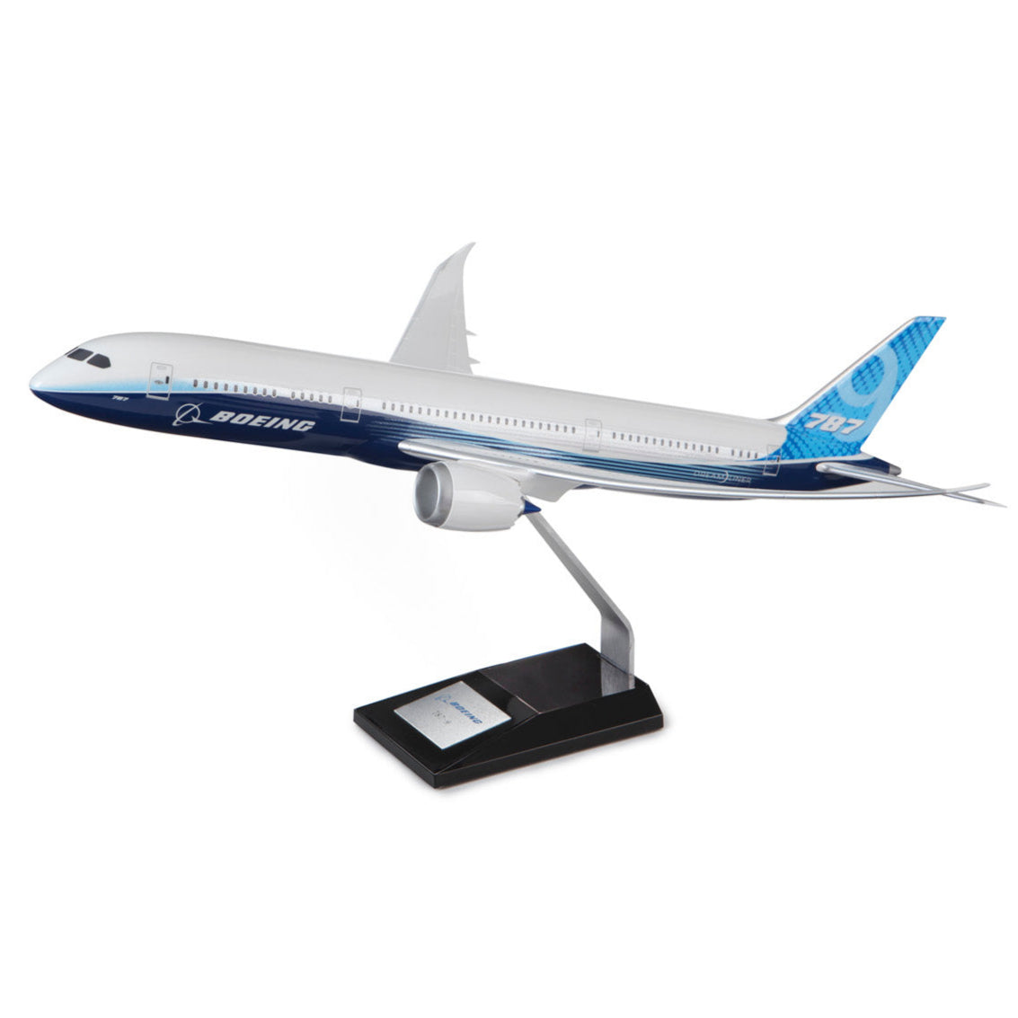 The Boeing Stores Boeing 787-9 Dreamliner Resin 1:100 Model features a blue and white color scheme, mounted on a stand with a black base and silver plaque. Boeing is proudly displayed on the side, highlighting its distinctive curved wingtips.