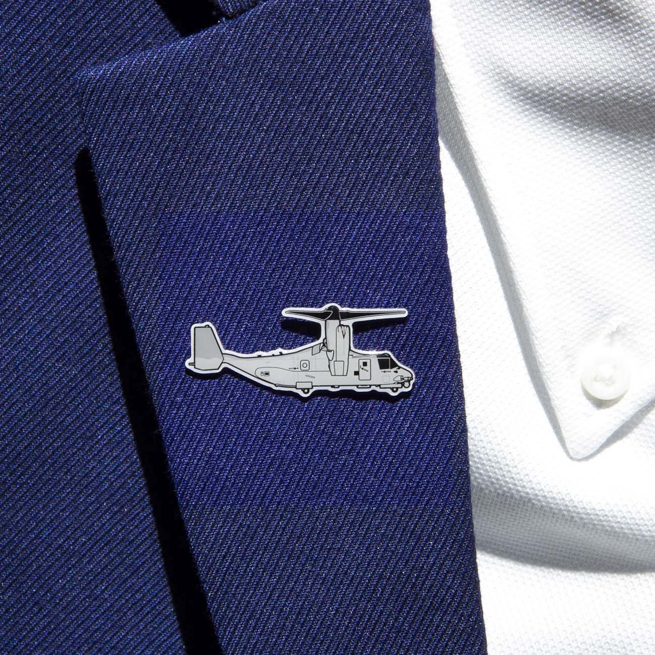 The Boeing Stores Boeing Illustrated V-22 Lapel Pin, in a silver tone with an aircraft outline and epoxy finish, adds elegance to the navy blue blazer lapel. It beautifully complements the white shirt beneath.
