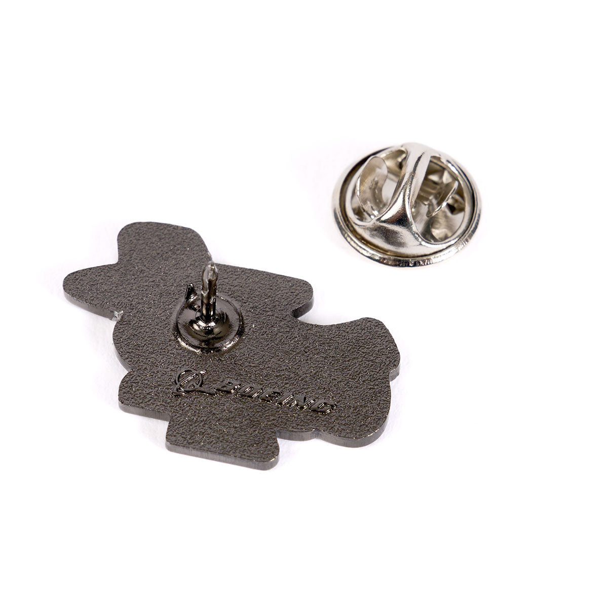 The backside of the Boeing Phantom Works Lapel Pin from The Boeing Store features a metal clasp that detaches to reveal a small pin post. Its dark, textured design resembles Phantom Works aesthetics, with engraved markings near the bottom and a shiny circular clasp reminiscent of cutting-edge aerospace tech.