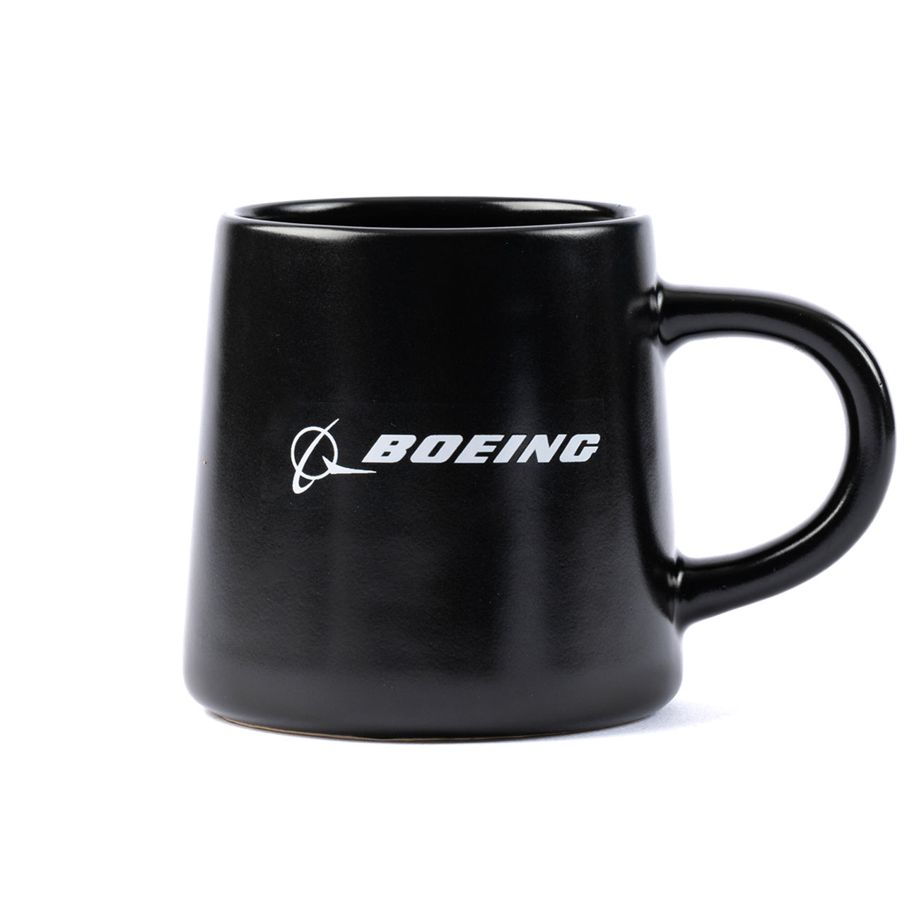 The Boeing Stores Boeing Airplane Company Logo Mug is a black ceramic cup with a white logo and aircraft graphic. It features a wide base that tapers slightly at the top, has a sturdy handle, and boasts a matte finish. The mug is microwave and dishwasher safe.