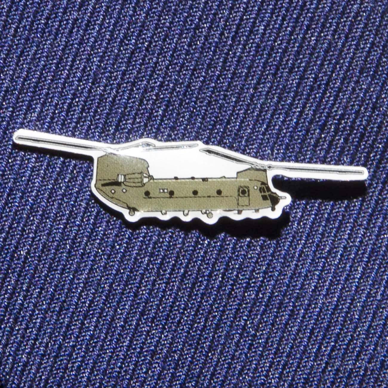 The Boeing Stores Boeing Illustrated CH-47 Lapel Pin is a small, silver-tone pin shaped like a military helicopter with two rotors, features an epoxy finish, and is attached to blue textured fabric.