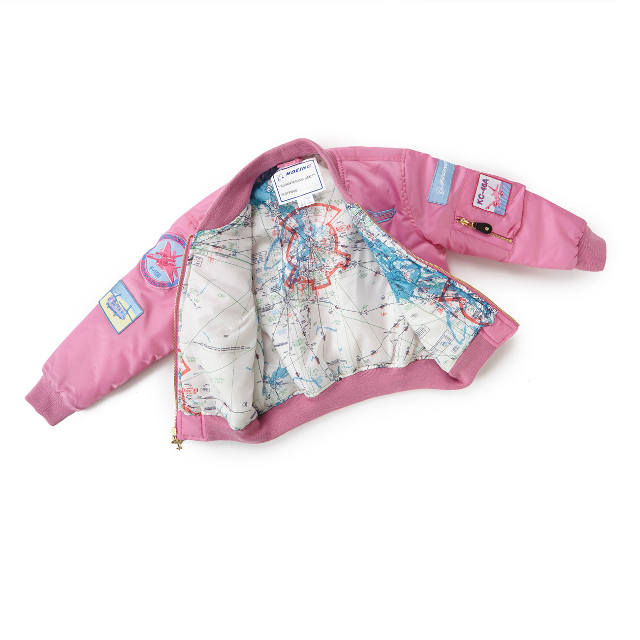 The Boeing Kids Pink Aviator Jacket from The Boeing Store features an aircraft and star patch, ideal for aviation fans. Its interior lining is designed like an aeronautical map with blue and red markings, adding a unique touch when worn open.