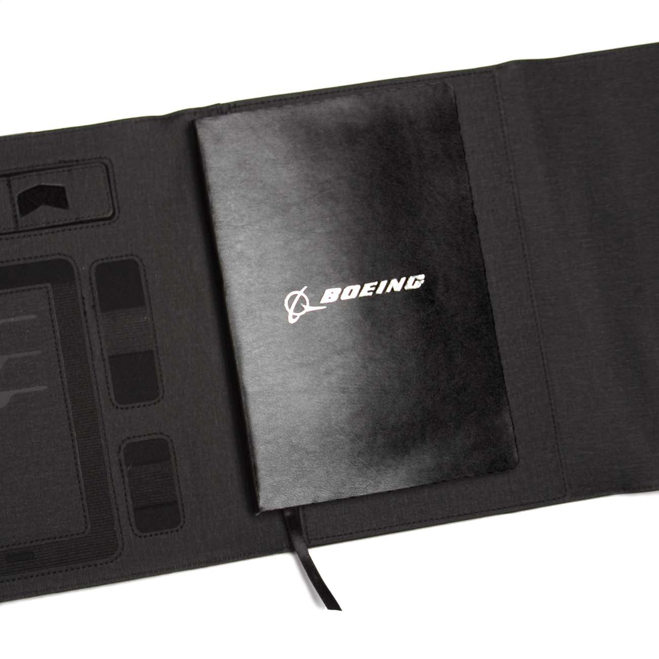 The Boeing Stores sleek Small Padfolio with Wireless Power Bank features a textured black surface adorned with a white Boeing logo, compartments, and discreet charging cables for seamless functionality.