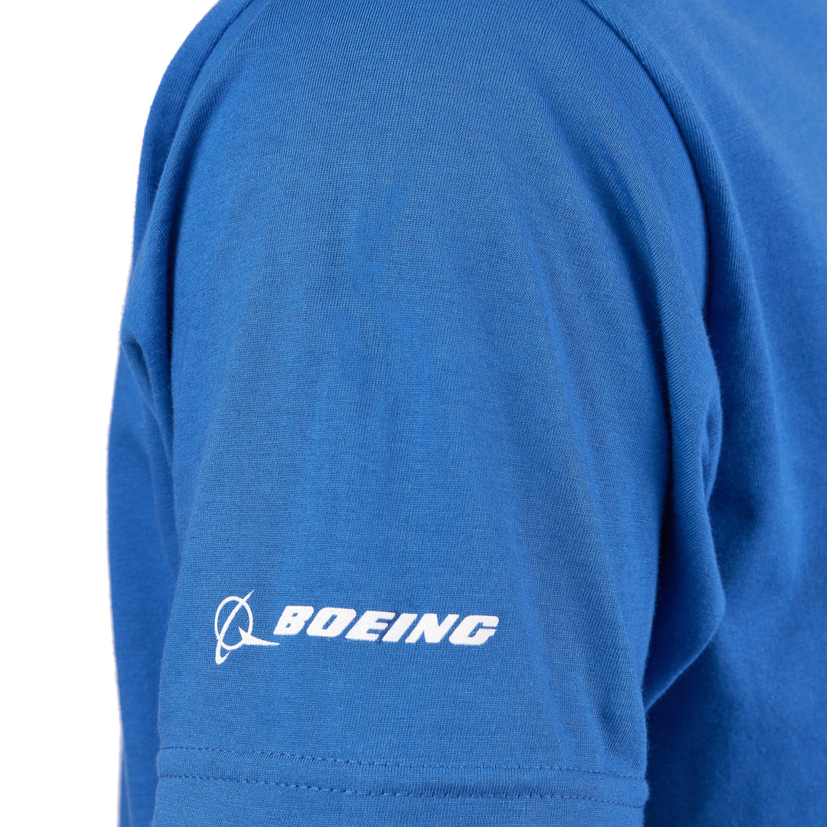 Aviation fan wearing The Boeing Stores Boeing 747 Stratotype Unisex T-Shirt in blue, made of preshrunk cotton with a white Boeing logo on the sleeve. Only part of their shoulder and sleeve is visible, emphasizing the fabric’s texture.