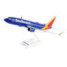 The Daron Southwest Airlines Boeing 737 MAX 8 1:130 Model is an injection molded plastic airplane designed for collectors, featuring a blue fuselage with the Southwest logo, a vivid red, yellow, and orange tail, and elegantly displayed on a white stand labeled with its model name.