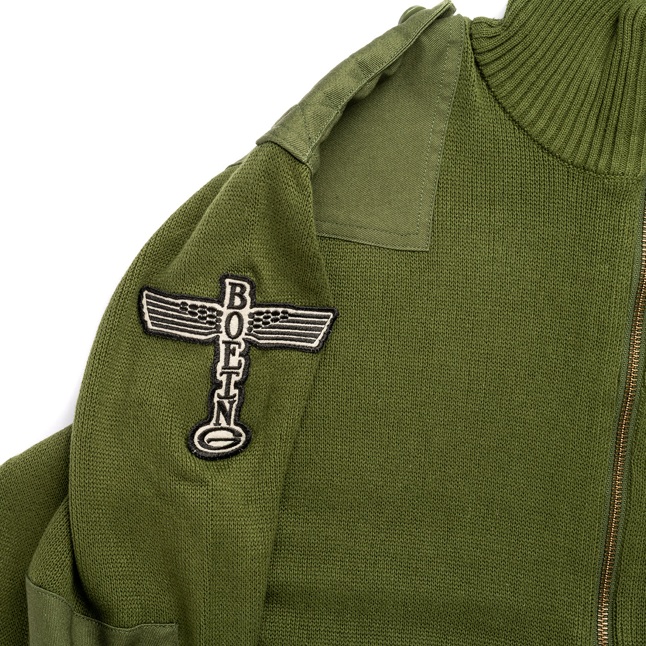 The Boeing Stores Red Canoe Boeing Airplane Logo Cardigan is a green jacket featuring a patch with a stylized propeller and Boeing in bold vertical letters. Made from 100% cotton, it includes a collar and durable YKK zipper.
