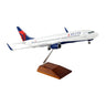 The Daron Delta Air Lines Boeing 737-800 1:100 Model comes with a wooden stand, ideal for collectors, and features the airlines livery on a white background.